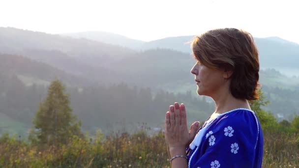 Kobieta modli się na szczycie góry podczas zachodu słońca. — Wideo stockowe