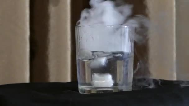 Ein Glas Wasser mit Trockenalkoholtablette und Rauch darin. — Stockvideo