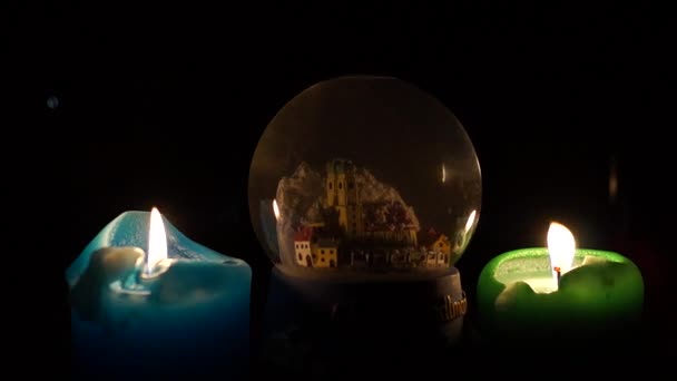 Uma lembrança redonda transparente com um castelo nele com duas velas coloridas . — Vídeo de Stock