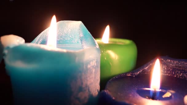 Drei brennende farbige Kerzen auf schwarzem Hintergrund. — Stockvideo