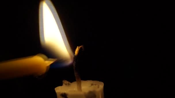 Una luz de vela delgada con otra . — Vídeos de Stock