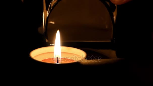 Una cacerola pequeña con una vela votiva en ella se pone dentro de una pequeña estufa en la noche . — Vídeo de stock