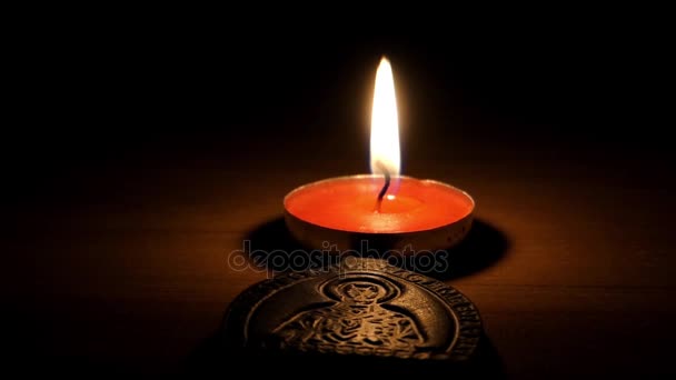 Osvětlené votivní svíčka stojící za malé dřevěné ikona Panny Marie v noci. — Stock video