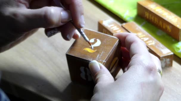 A Woman`s Hand Painting a Number on a Wooden Cube With a Round Tip Paintbrush — Stock Video