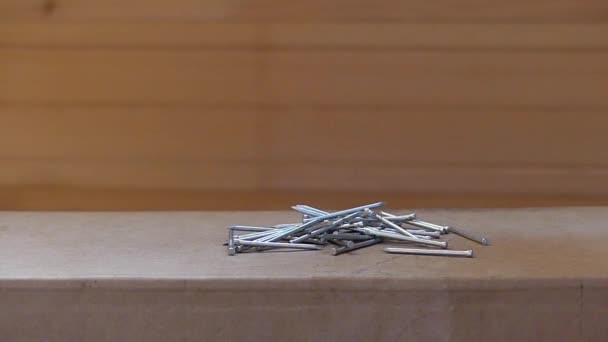 Een zwarte magneet trekken aluminium nagels aan zichzelf op een houten tafel. — Stockvideo