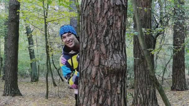 En ung rolig Man kikar ut och ropade något i en höst-skog. — Stockvideo