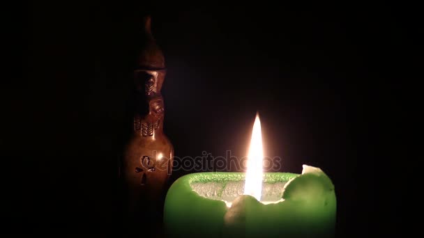 Una vela verde brillante una estatua de pájaro egipcio de pie cerca por la noche . — Vídeos de Stock