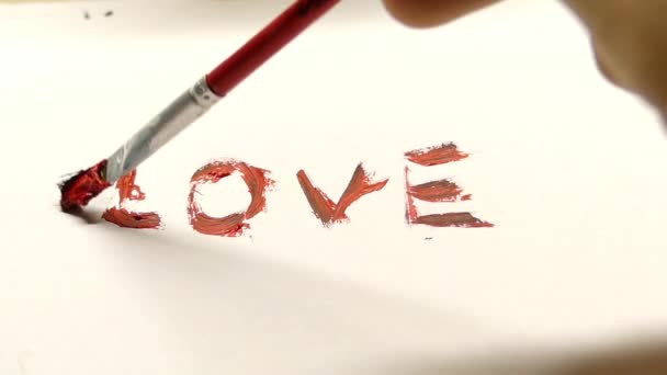 Een Hand schilderij uit het woord 'liefde' met behulp van rood bruine kleur — Stockvideo