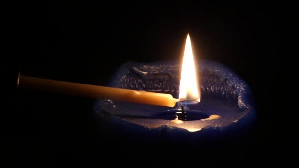 Eine dünne Kerze, die nachts eine dicke dunkelblaue entzündet. — Stockvideo