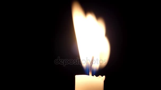 Eine brennende Kerzenflamme blinkt im schwarzen Hintergrund. — Stockvideo