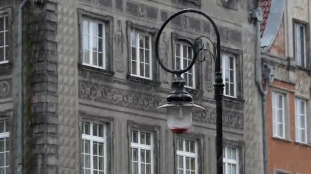 Een oude Fashined lantaarnpaal, staande in de buurt van een Xix eeuw Europese gebouw met zware sneeuw vallen — Stockvideo