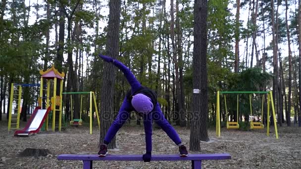 Енергійний молоду жінку, робити йога вправи на лавці починається нахилу і підвищення її боку. — стокове відео