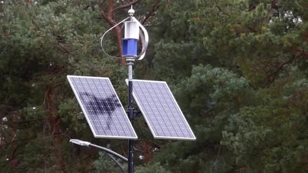 Um sensor meteorológico giratório com dois painéis solares anexados nas proximidades em pé contra o fundo da floresta. Energia verde . — Vídeo de Stock