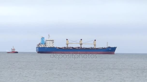 Obrovské modré a červené ropného tankeru a malý remorkér plovoucí v moři vlnitý na podzim — Stock video