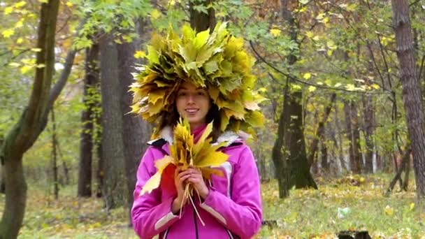 Усміхнена дівчина з вінком листя на голові в лісі . — стокове відео