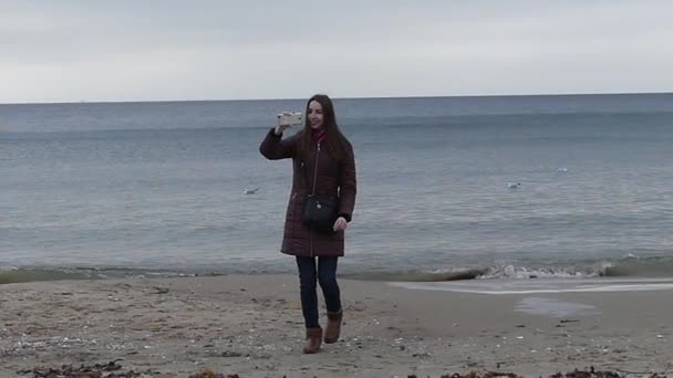 Una buena chica está tomando fotos y corriendo de una sealina a un fotógrafo en cámara lenta . — Vídeos de Stock