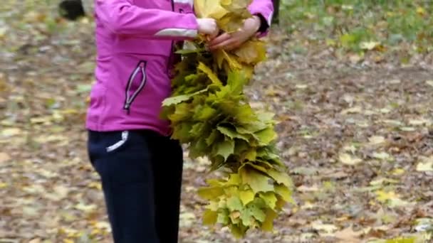 Flickan i skogen gör kransen av gula löv. — Stockvideo