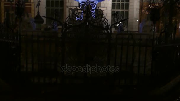 Un hermoso palacio viejo europeo con una escultura romana clásica de pie sobre un pedestal azul bien iluminado por la noche . — Vídeo de stock