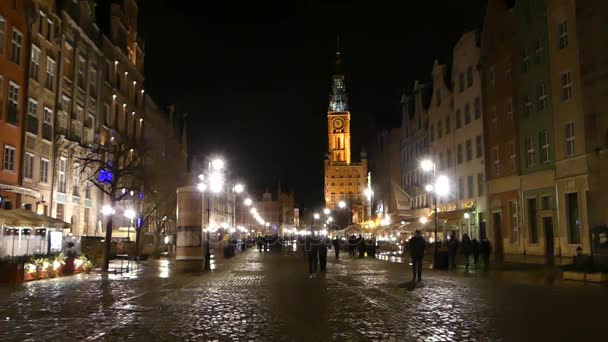 Dobře osvětlená polské město Street s staré kostelní věž v noci a lidé procházky podél ní — Stock video