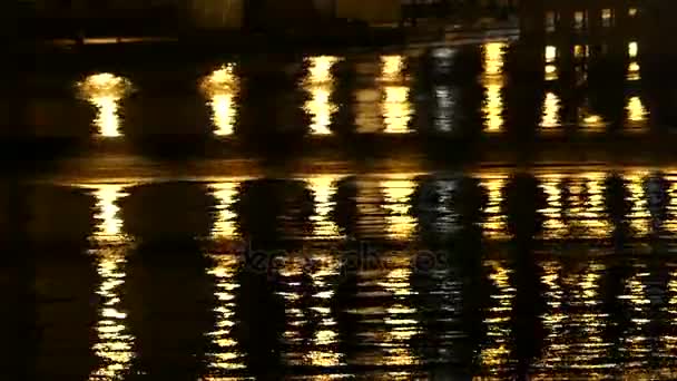 Águas pretas e brancas em uma lagoa da cidade que dá reflexos amarelos da coluna com um cais perto — Vídeo de Stock