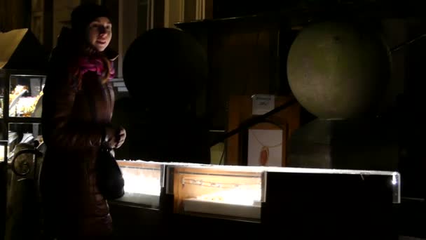 Une jeune fille regardant un stand lumineux dans un magasin de fenêtre avec de grandes globes en elle la nuit — Video