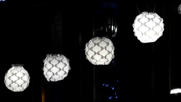 Four White Round Ceiling Plafonds With Curvy Surface Hanging in a Shop at Night — Stock Video