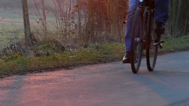 La vue rapprochée sur les pieds d'un jeune cycliste, se déplaçant sur un vélo avec lampe de tête allumée, le long d'une route de campagne le matin à l'automne — Video
