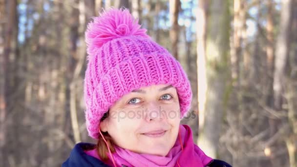 Hermosa mujer de mediana edad emocional escuchando música en los auriculares y sonriendo a la cámara y agitando su mano en video 4k . — Vídeos de Stock