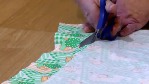 Mãos com tesouras cortar o tecido verde . — Vídeo de Stock