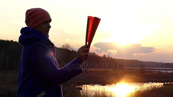 很棒的女人展开的照射下的日落太阳早春在东欧橙色手持风扇 — 图库视频影像