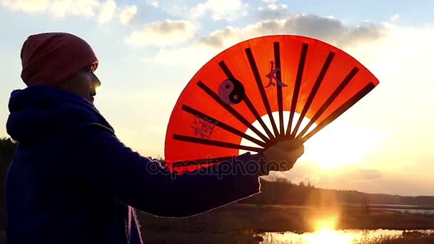Женщина разворачивает апельсиновую ручку под лучами закатного солнца ранней весной в медленном движении . — стоковое видео