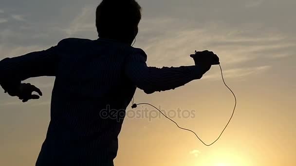 Jeune homme énergique danse en plein air en regardant un coucher de soleil, tout en étant sur une pelouse d'un certain champ au ralenti . — Video