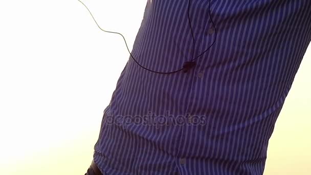 Young Man is Dancing With Earbuds in Hands With the Grey Cloudy Sky in the Background in the Early Spring in Slow Motion — Stock Video