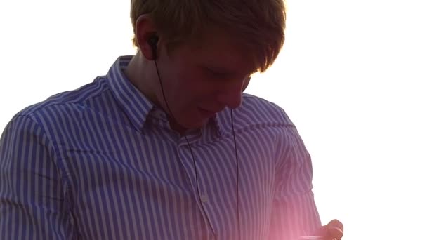Młody człowiek jest stojący w polu i patrząc na jego Palyer z ładny zachód słońca promienie w Backgroung w zwolnionym tempie — Wideo stockowe