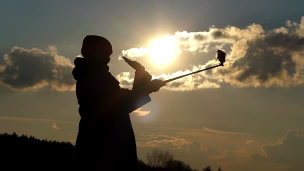 Atraktivní žena je mával jí ruku a Selfie fotografie během působivý západ slunce v brzy na jaře — Stock video