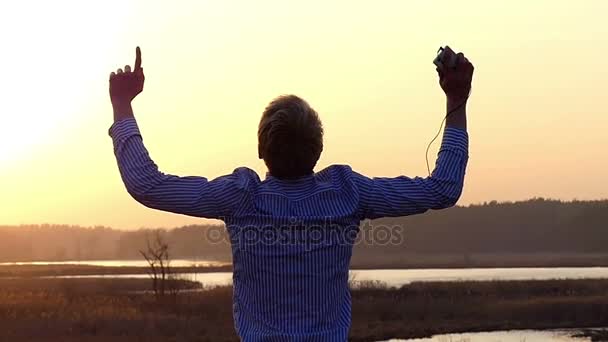 Fair Headed Young Man Cheio de Emoções Positivas está Dançando e Fazendo Movimentos de Ondas em um Gramado Ao Ar Livre Energeticamente em Movimento Lento — Vídeo de Stock