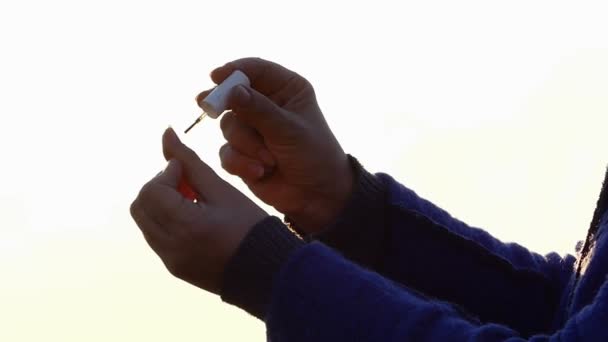 Handen van een vrouw die betrekking heeft op haar nagels met make-up Pools op de zonsondergang in het vroege voorjaar — Stockvideo