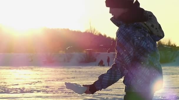 Niño jugando con la espada y la nieve en cámara lenta al atardecer . — Vídeos de Stock