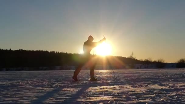 A síelő lovagol egy sí a befagyott tavon naplementekor a lassú mozgás. — Stock videók