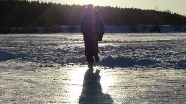 Küçük çocuk ağır çekimde buz gölde günbatımı sırasında kayma. — Stok video