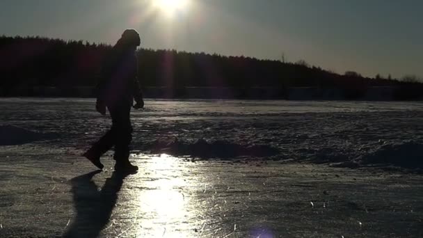 Pequeño niño caminando en el lago de hielo en cámara lenta durante la puesta del sol . — Vídeos de Stock