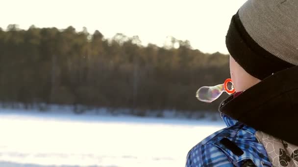 Boy in Slow Motion Blow Bubbles Into the Air en invierno. Vista trasera . — Vídeos de Stock