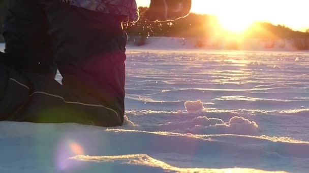 Niño caminando sobre su rodilla sobre la nieve en el parque al atardecer . — Vídeo de stock
