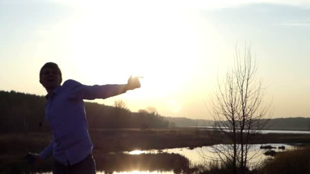 Coucher de soleil impressionnant et danse énergique d'un jeune homme au bord d'un lac forestier au début du printemps au ralenti — Video