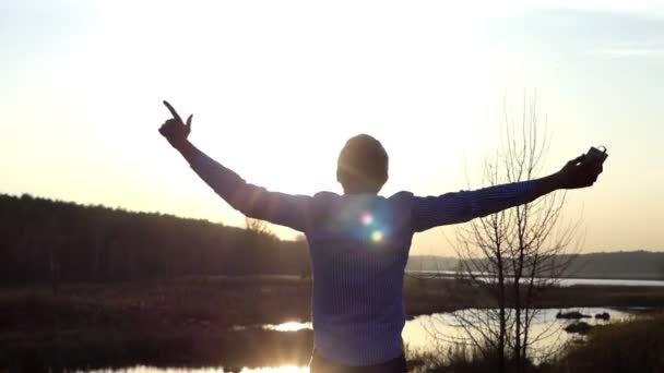 Pôr-do-sol incrível e uma dança energética de um jovem no banco de um lago florestal no início da primavera — Vídeo de Stock