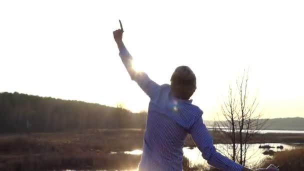 令人印象深刻的日落和一个年轻人在早春森林湖岸上能量舞蹈 — 图库视频影像