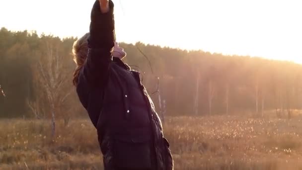 Junger Mann tanzt mit Ohrhörern in den Ohren bei eindrucksvollem Sonnenuntergang im Freien in einem zeitigen Frühling in Zeitlupe — Stockvideo