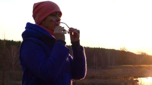 Mooie vrouw is op zoek bij zonsondergang op de oever van het Picturesque Lake in het vroege voorjaar in Oost-Europa — Stockvideo