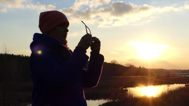 Trevligt utseende kvinna tittar på solnedgången på stranden av sjön pittoreskt tidigt på våren i Östeuropa — Stockvideo