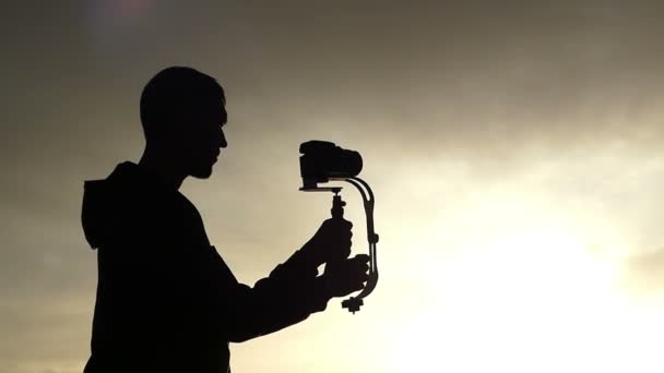 Splendid Sunset and a Silhouette of a Cameraman Shooting Video. — Stock Video